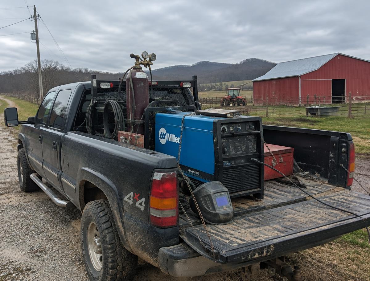 Welding truck with welder and gas cylinders parked on a rural farm road